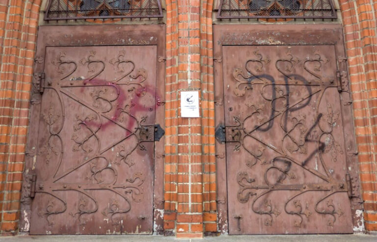 Piorun i napisy „JP” na drzwiach kościoła w Olsztynie